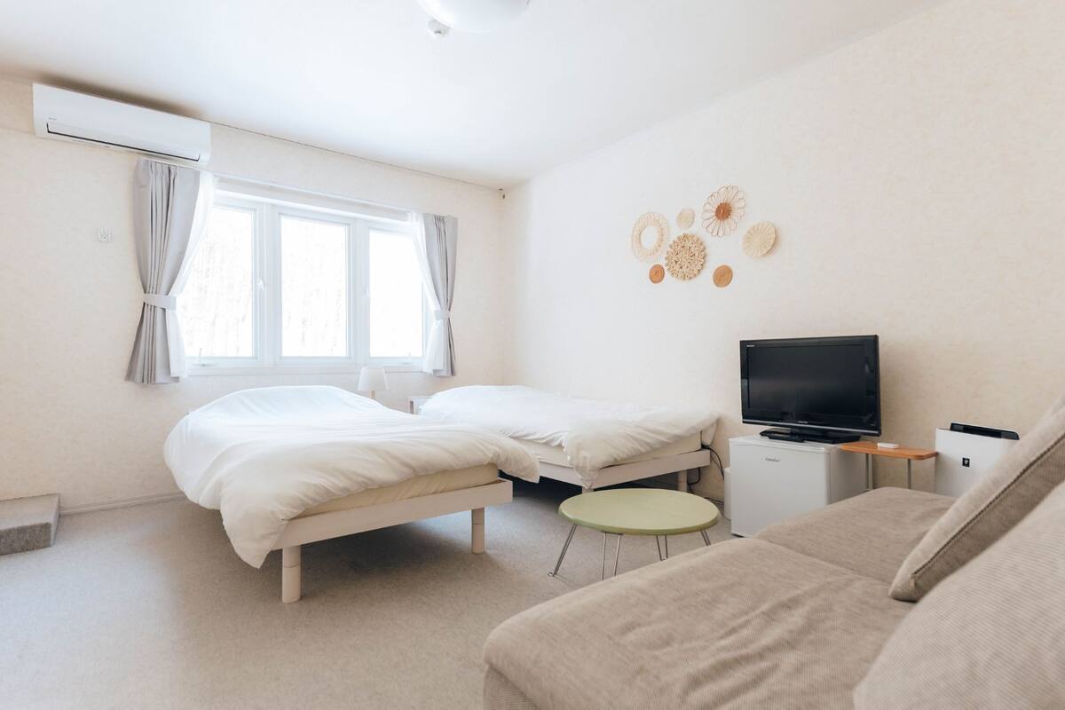 Une chambre à coucher avec un lit, une télévision, une petite table et un canapé.
