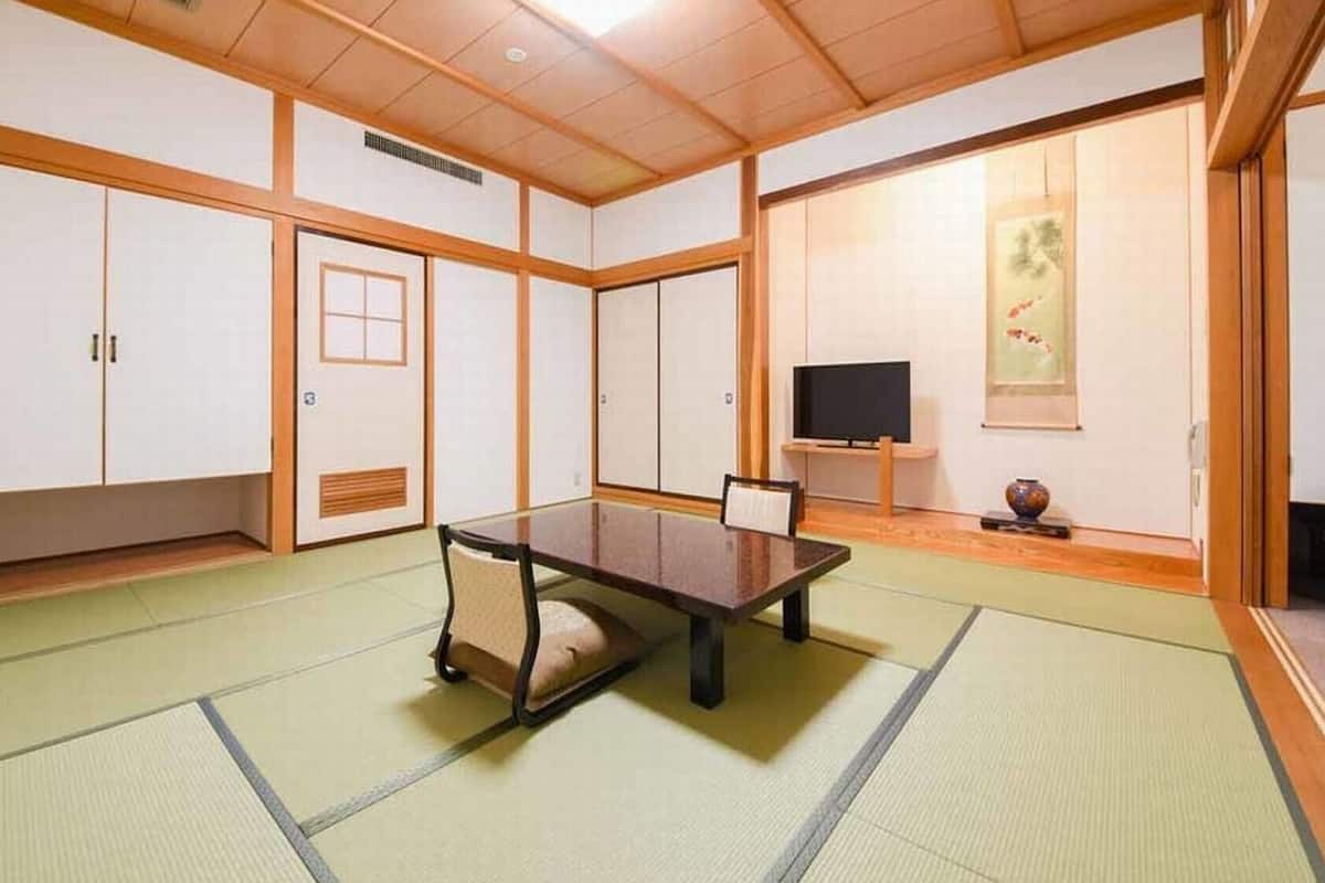 Een traditionele Japanse kamer met tatami vloerbedekking, een lage tafel, schuifdeuren en een televisie.