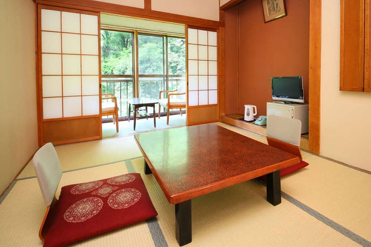 Een traditionele Japanse kamer met tatami vloerbedekking, een lage tafel en schuifdeuren.