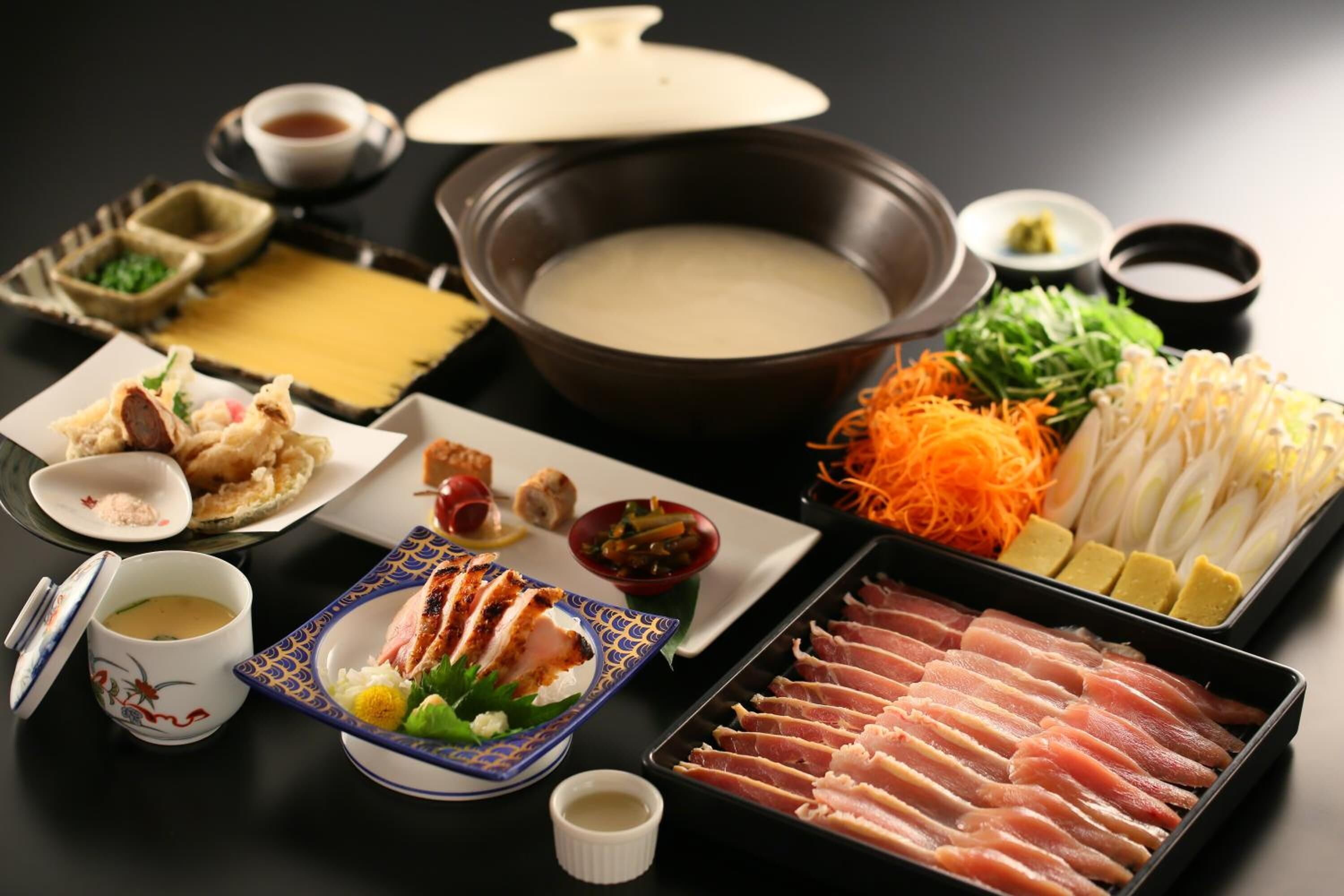 Una configuración tradicional japonesa de olla caliente con diversos ingredientes y acompañamientos.