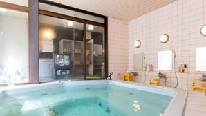 Un baño moderno con una bañera grande, un televisor y una zona de ducha.