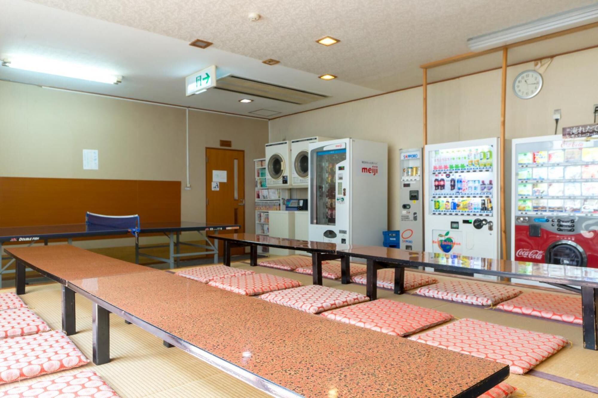 A room with a long table, multiple washing machines, and vending machines.