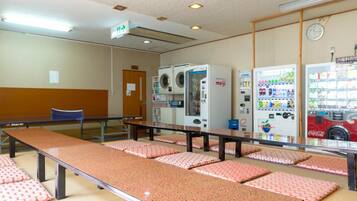 A room with a long table, multiple washing machines, and vending machines.