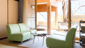 Una habitación con dos sofás verdes, una mesa de centro de vidrio y una silla.
