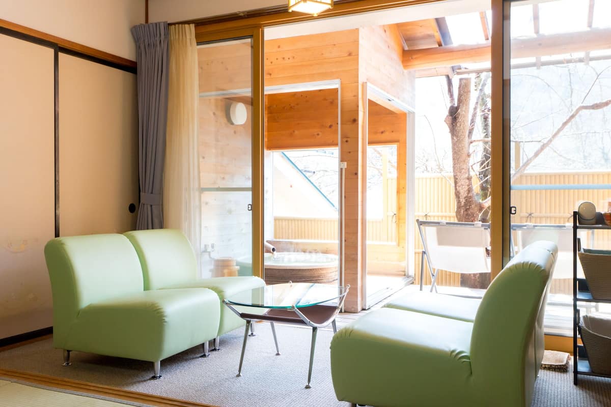 Una habitación con dos sofás verdes, una mesa de centro de vidrio y una silla.