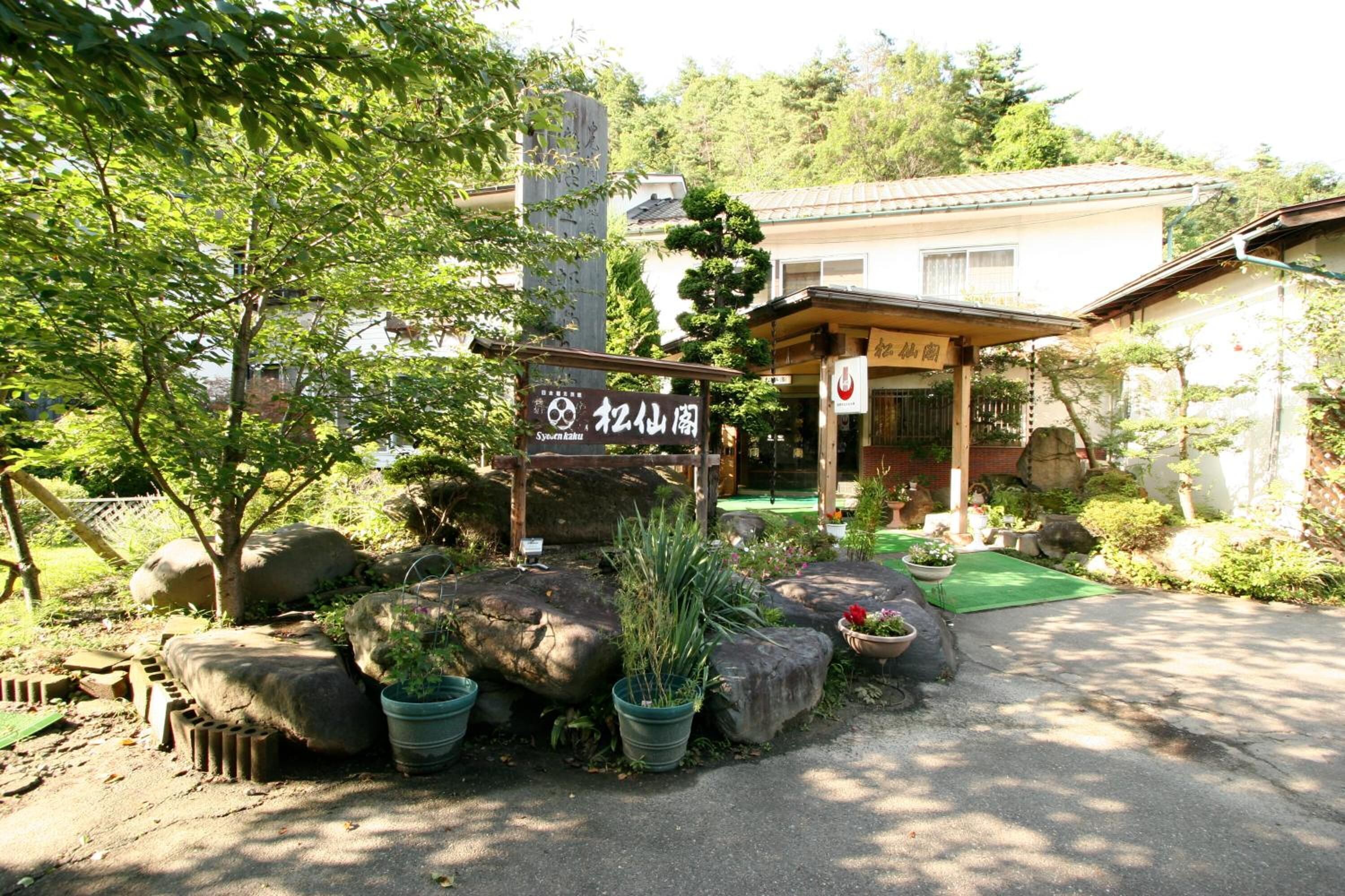 A traditional Japanese building with a wooden entrance and a signboard.