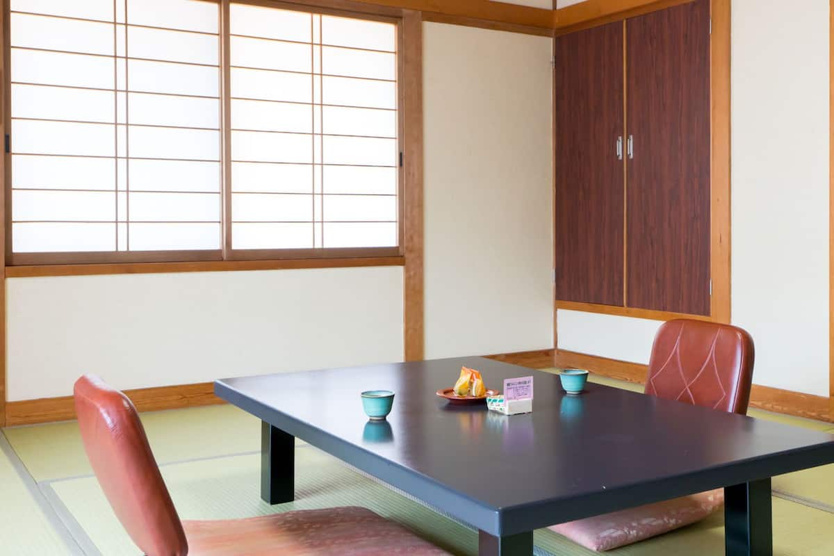 Una habitación japonesa tradicional con suelo de tatami, una mesa baja y una puerta corredera.