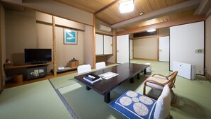 Ett traditionellt japanskt rum med tatamimattor på golvet, ett lågt bord, stolar, en tv och en värmare.