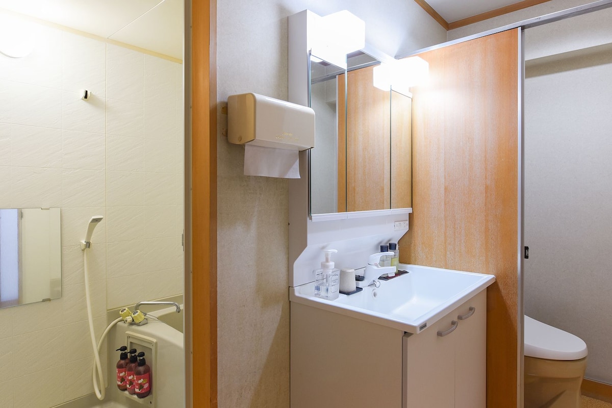 A bathroom with a white sink, a mirror, a toilet, and a shower area.