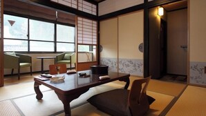 A traditional Japanese room with tatami flooring, a low table, chairs, and sliding doors. - Yutagawa Onsen Kuhe Ryokan Tamaya (Tsuruoka)