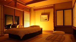 A traditional Japanese-style room with tatami flooring, a bed, a desk, and a sliding door. - Yutagawa Onsen Kuhe Ryokan Tamaya (Tsuruoka)