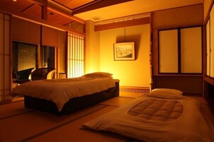 Una habitación tradicional japonesa con suelo de tatami, una cama, un escritorio y un puertas correderas.