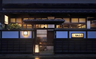 Un edificio japonés tradicional con fachada de madera, un acceso cubierto y señalización iluminada.