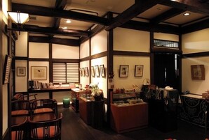 Un interior japonés tradicional con suelo de tatami, vigas de madera y un mostrador de recepción con fotografías enmarcadas.