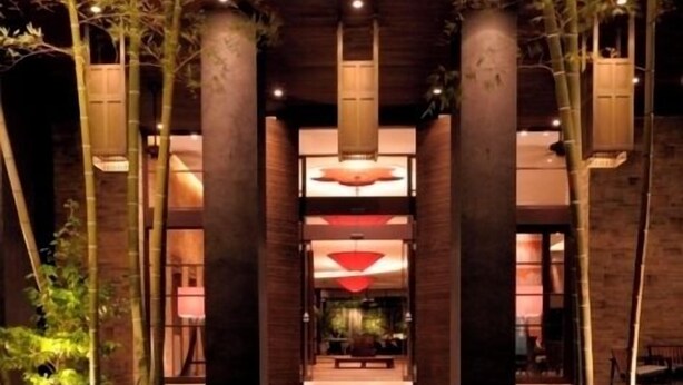 A pathway leading to a building with large pillars and hanging lanterns, surrounded by trees. - Konaya Hotel (Kofu)