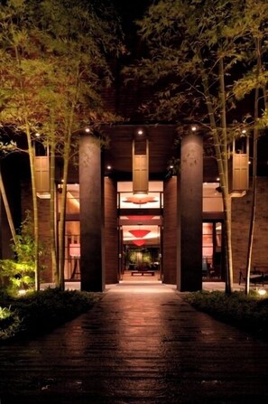 A pathway leading to a building with large pillars and hanging lanterns, surrounded by trees. - Konaya Hotel (Kofu)