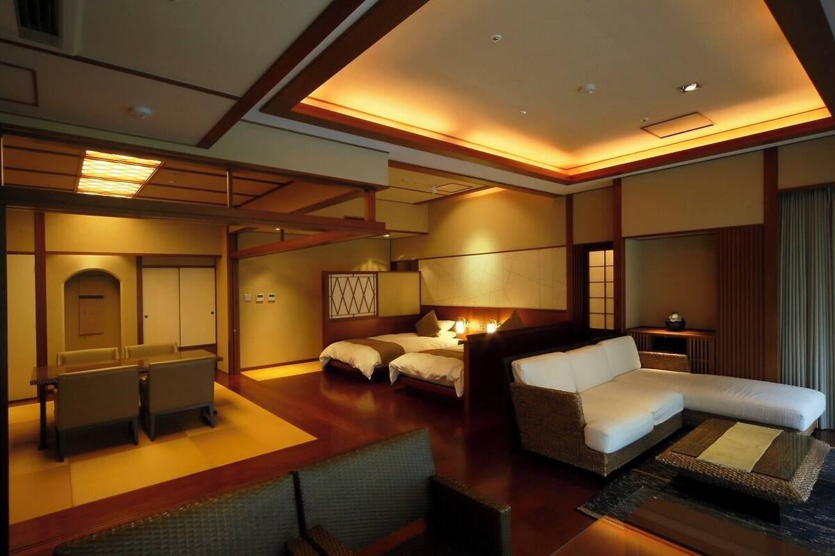 A hotel room with a bed, a sofa, a desk, and a chair.