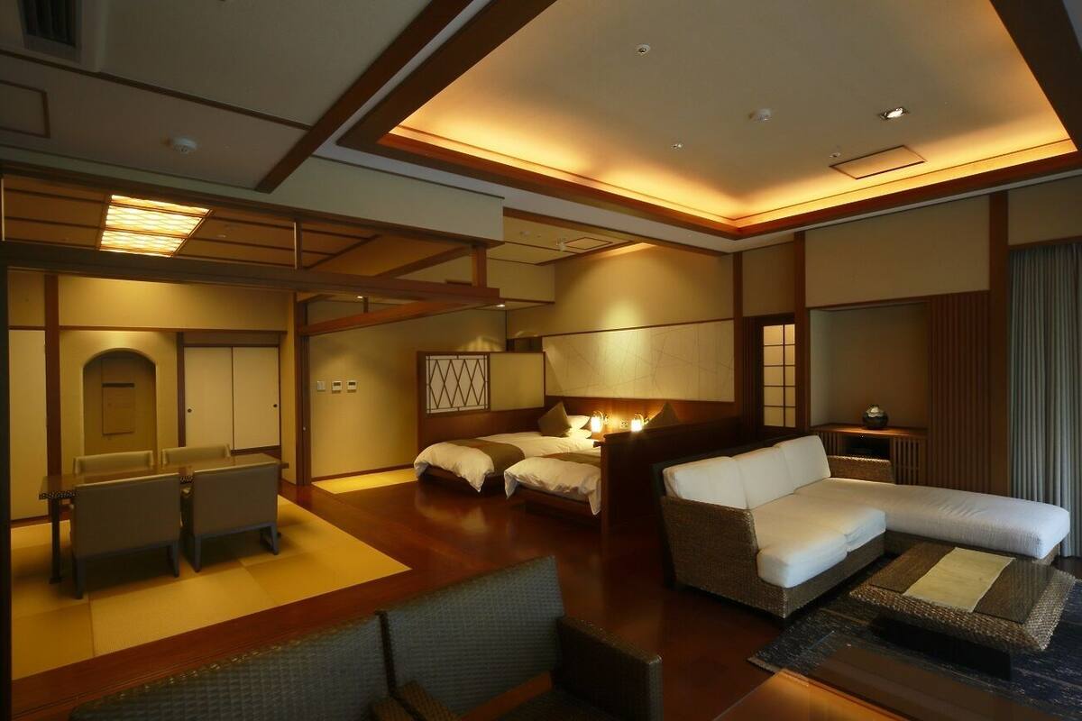 A hotel room with a bed, two bedside tables, a sofa, a desk, and a chair.