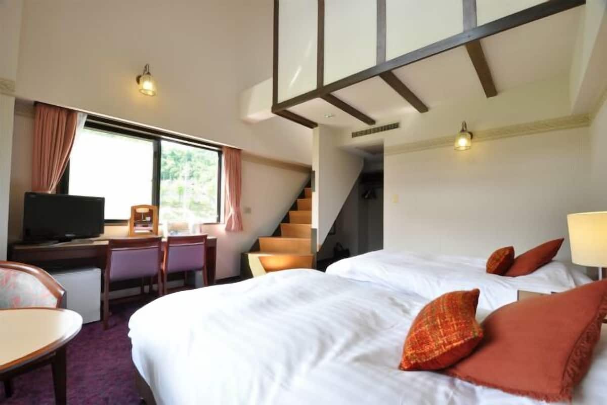 Ein Hotelzimmer mit einem Bett, einem Schreibtisch mit Fernseher, einem Sessel und einer Treppe.