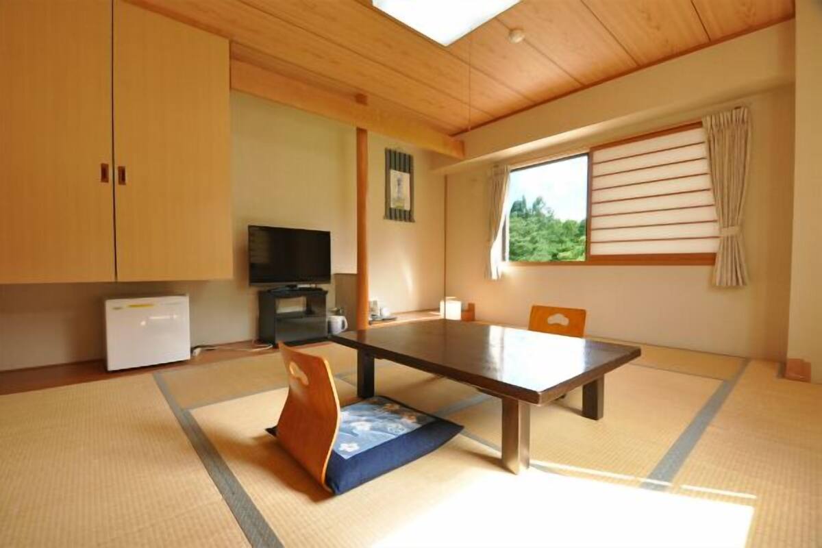 Ein traditioneller japanischer Raum mit Tatami-Bodenbelag, einem niedrigen Tisch und Schiebetüren.