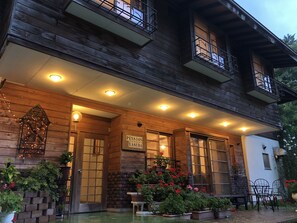 A wooden building with a porch, potted plants, and a sign reading "Pension Yasuda". - Inn of Amigos Yasuda Pension (Takayama)