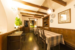 A dining area with wooden beams, a checkered tablecloth, and a mirror on the wall. - Inn of Amigos Yasuda Pension (Takayama)