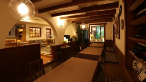 A cozy restaurant with wooden beams, tables, and chairs, and a view of the outdoors. - Inn of Amigos Yasuda Pension (Takayama)