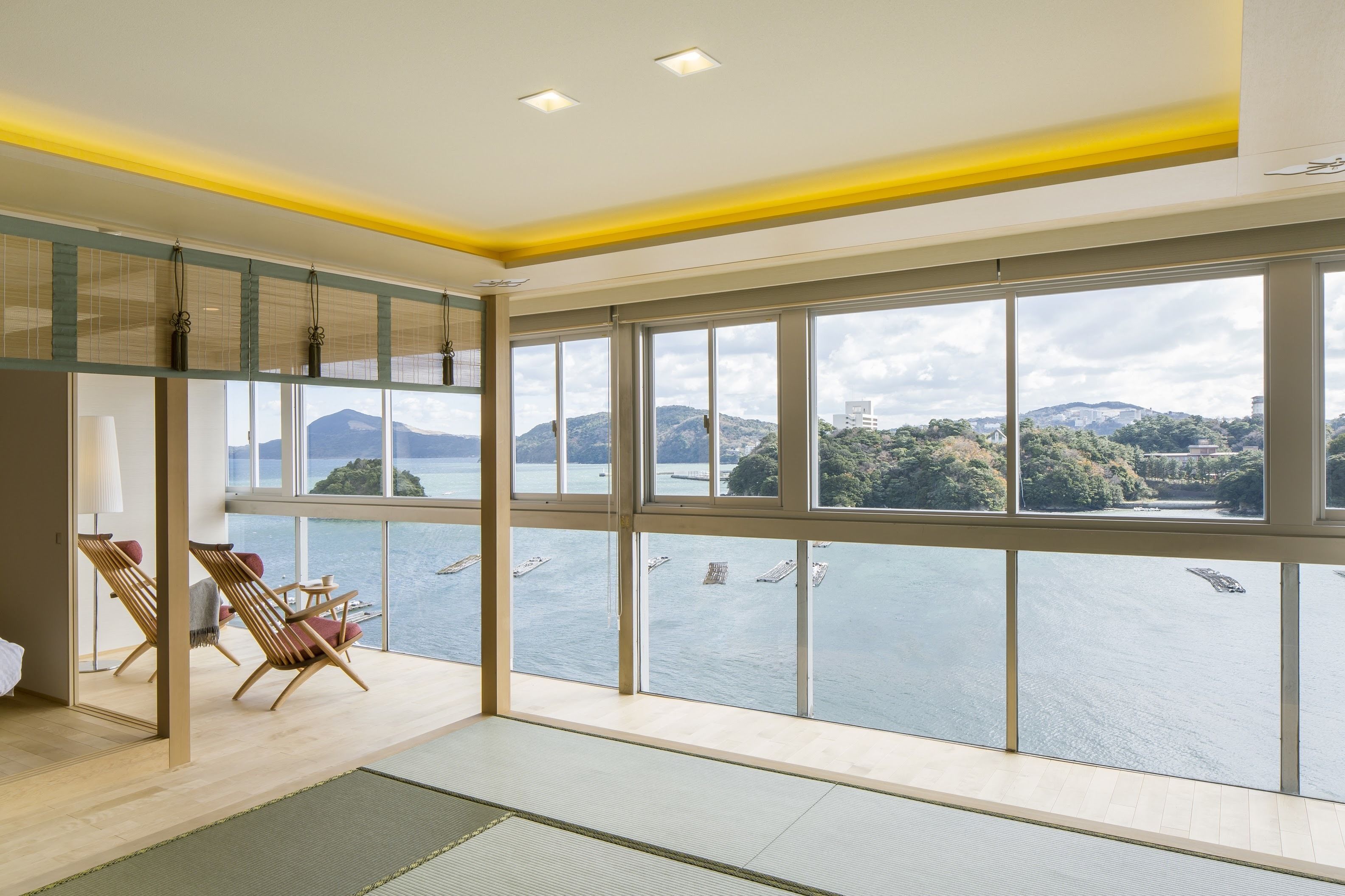 A spacious room with large windows overlooking a body of water and distant mountains.