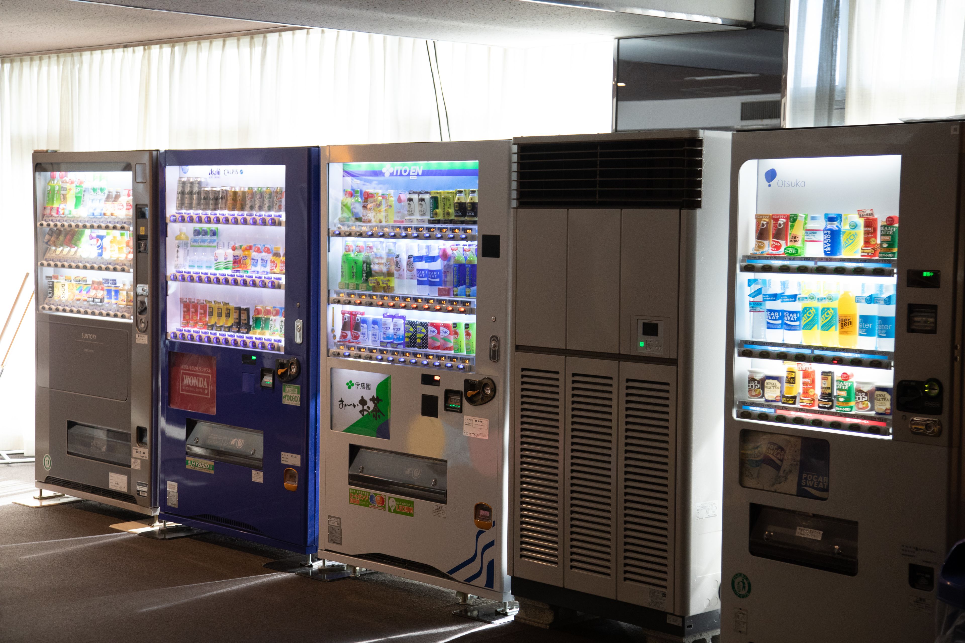 A row of vending machines with various beverages and snacks.