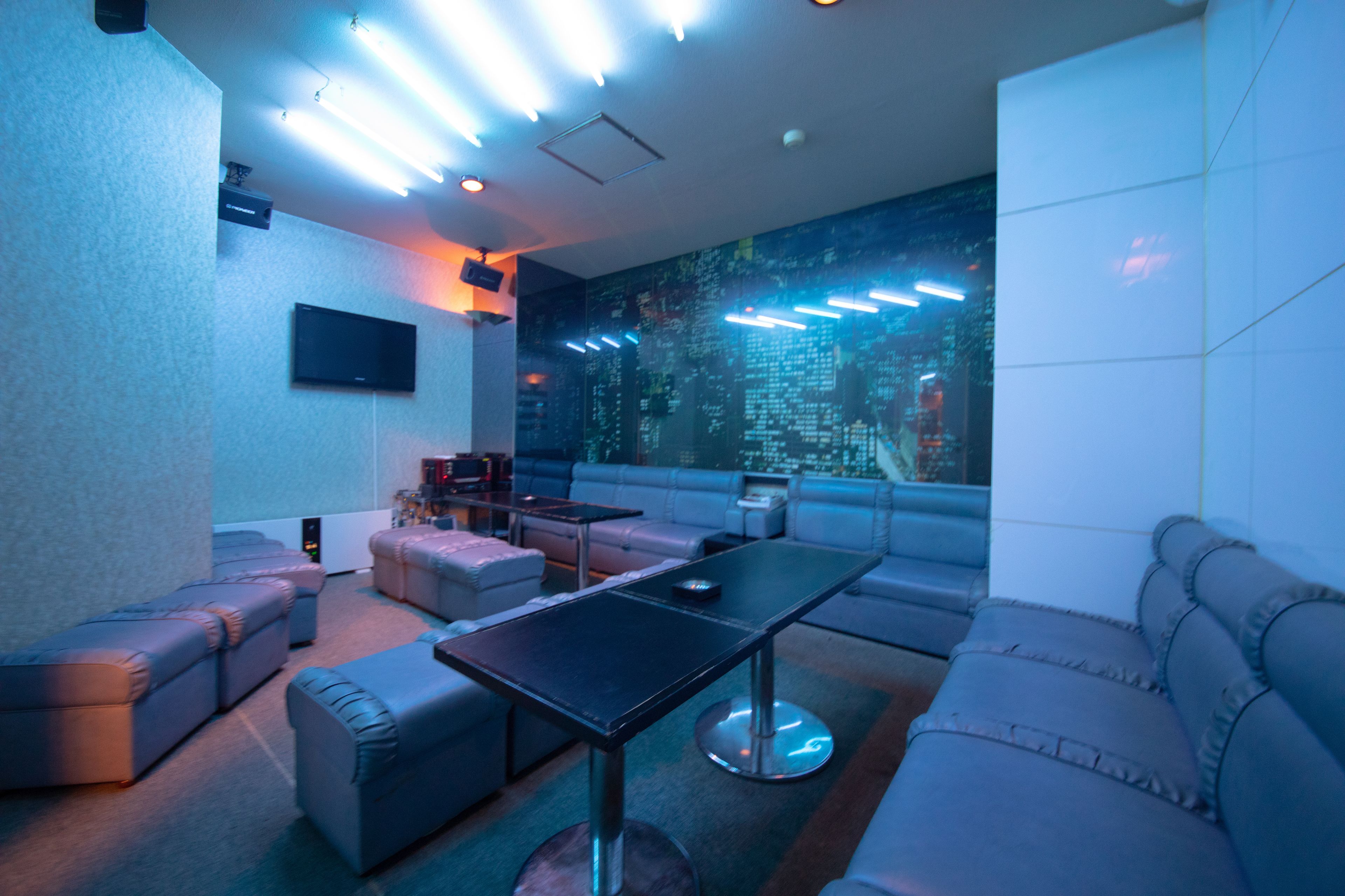 A modern lounge area with leather sofas, a central table, and a large wall-mounted screen.