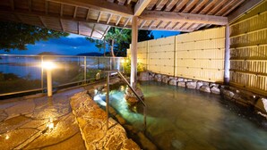 A hot spring area with stone steps leading into the water, a wooden pergola overhead, and a bamboo fence in the background. - Toba Grand Hotel (Toba)