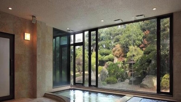 A spacious indoor area with a large window, a small pool, and a stone floor. - Hotel Rich Garden (Izumo)