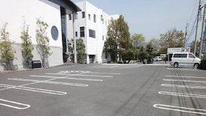 A parking lot with marked spaces and a building in the background. - Hotel Rich Garden (Izumo)
