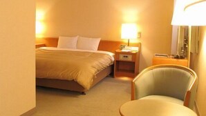 Une chambre d’hôtel avec un lit, des tables de chevet, une chaise et une petite table.