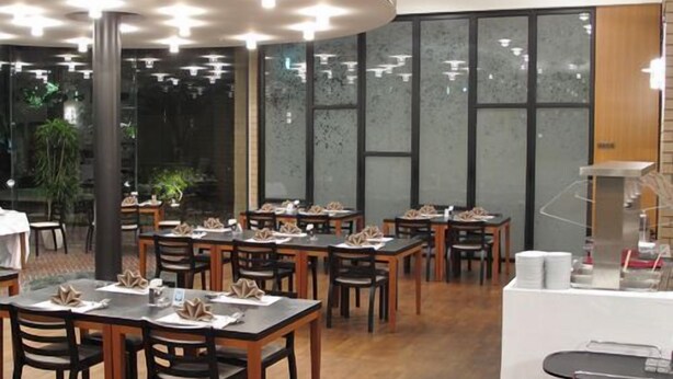 Un restaurant doté de nombreuses tables et chaises, d’un chariot de service et de grandes fenêtres.