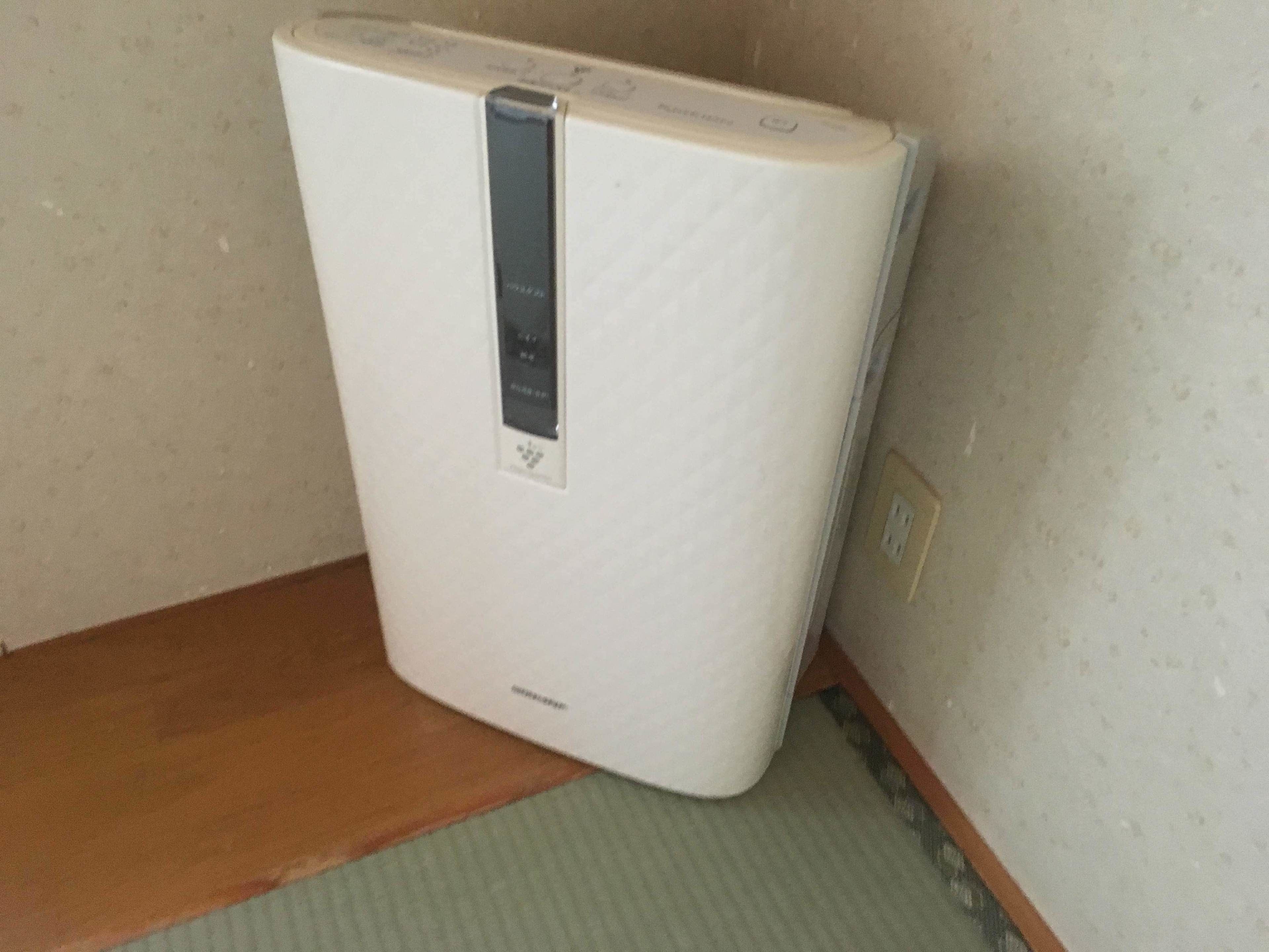 A white portable heater with a control panel, placed on a tatami mat floor.