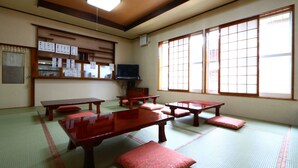 Una habitación tradicional japonesa con suelo de tatami, mesas de madera y puertas correderas.