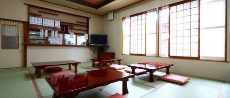 A traditional Japanese room with tatami flooring, wooden tables, and sliding doors.