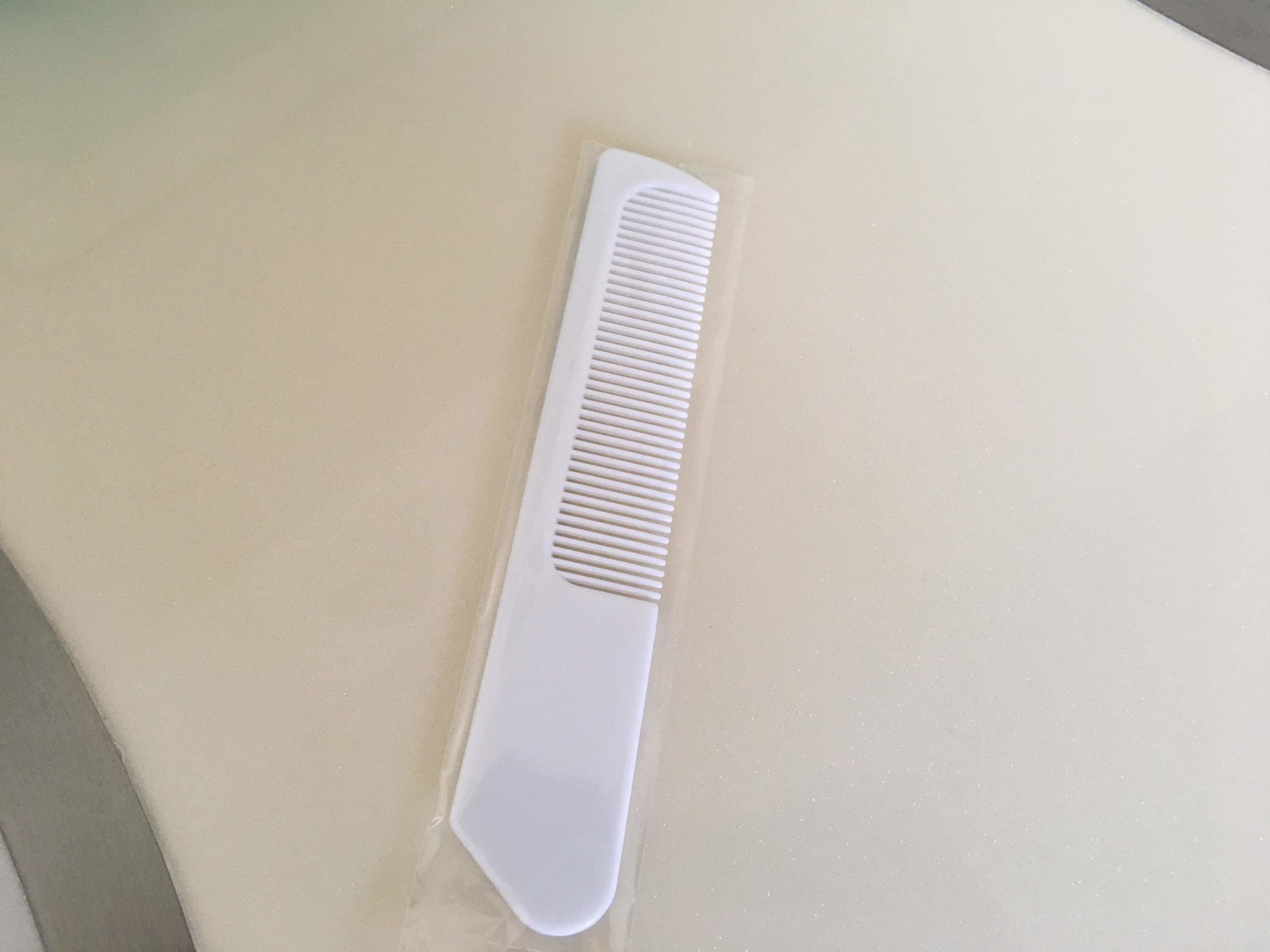 A white comb on a beige surface.