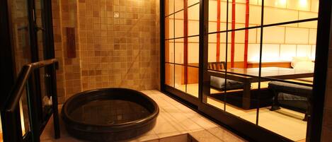 A traditional Japanese-style room with tatami flooring, a tatami mat seating area, and a sliding door leading to a private space.