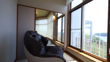 Un fauteuil de massage dans une pièce dotée de grandes fenêtres donnant sur un plan d’eau et un bâtiment.