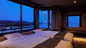 A hotel room with a large bed, a seating area, and a view of the sea. - Resort Hills Toyohama SORA no KAZE (Toba)
