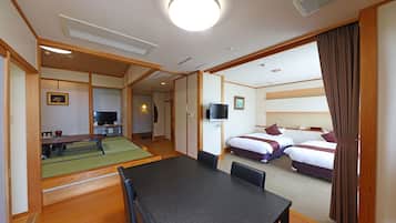 A hotel room with a dining area, two beds, a TV, and a ceiling fan.