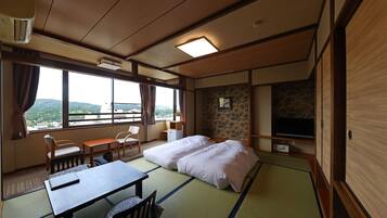 A traditional Japanese-style room with tatami flooring, a bed, a desk, and a television.