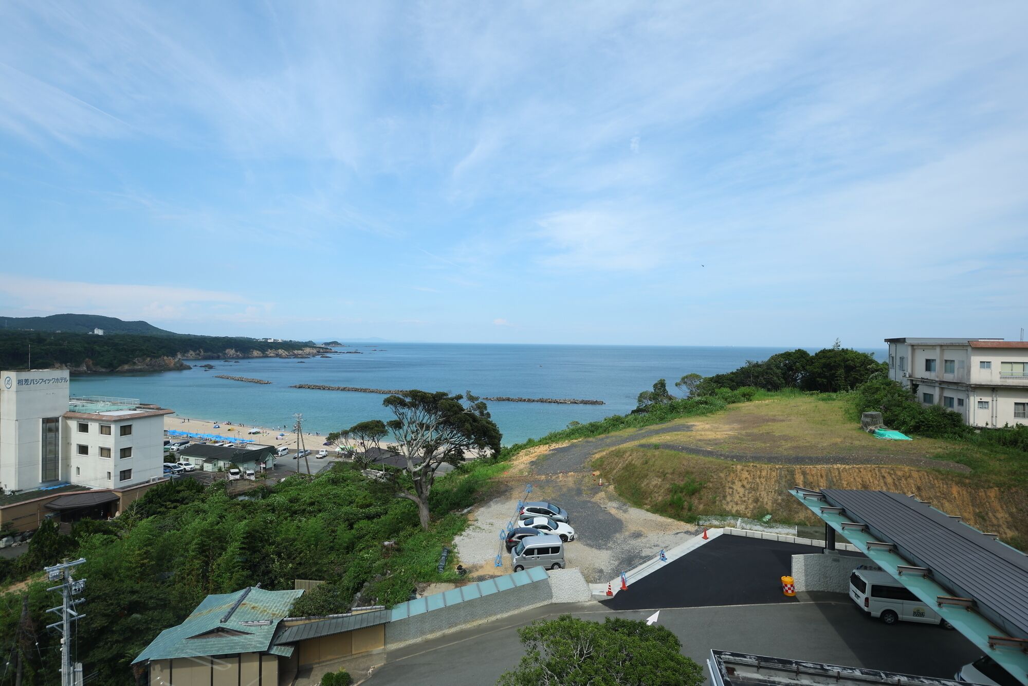 Vista costera con playa, zona de estacionamiento y edificios.