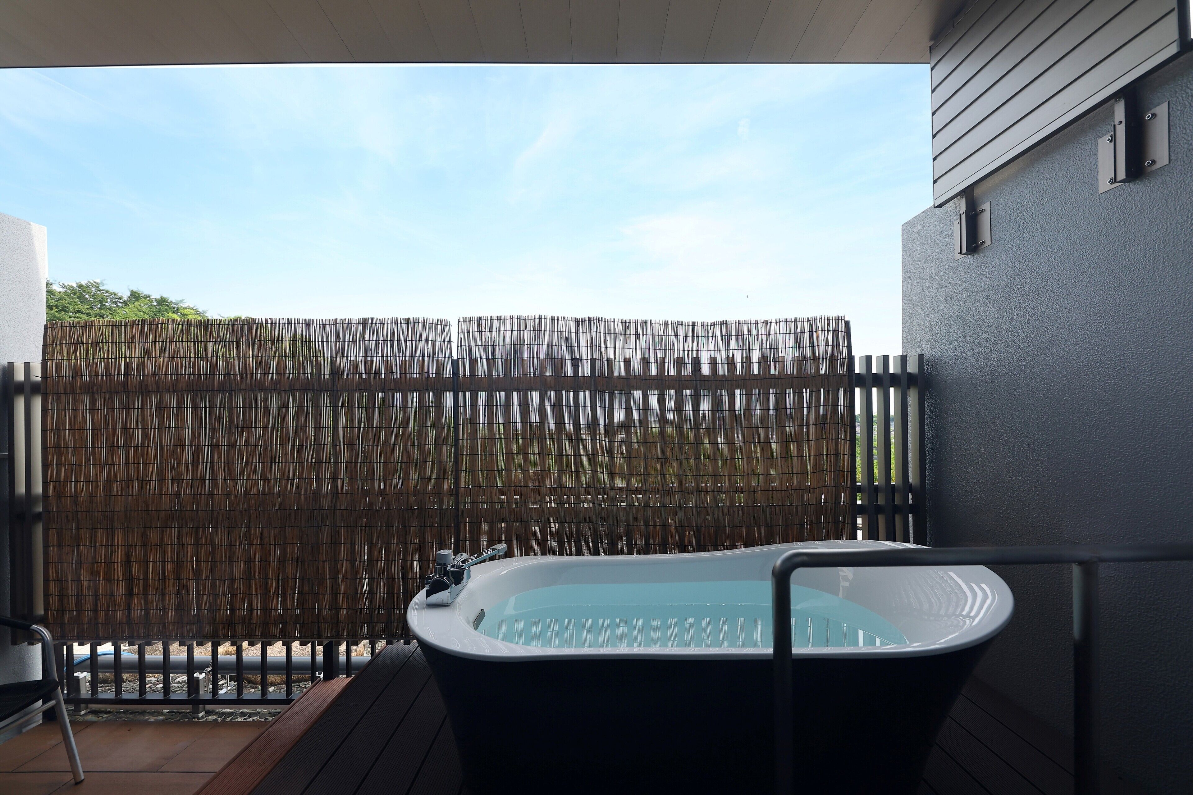 A hot tub on a balcony with a bamboo fence in the background.