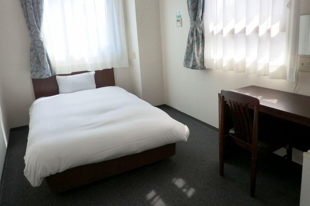A hotel room with a bed, a desk, and a chair.