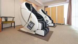 Una habitación con sillones de masaje, un banco y un amplio ventanal con cortinas.