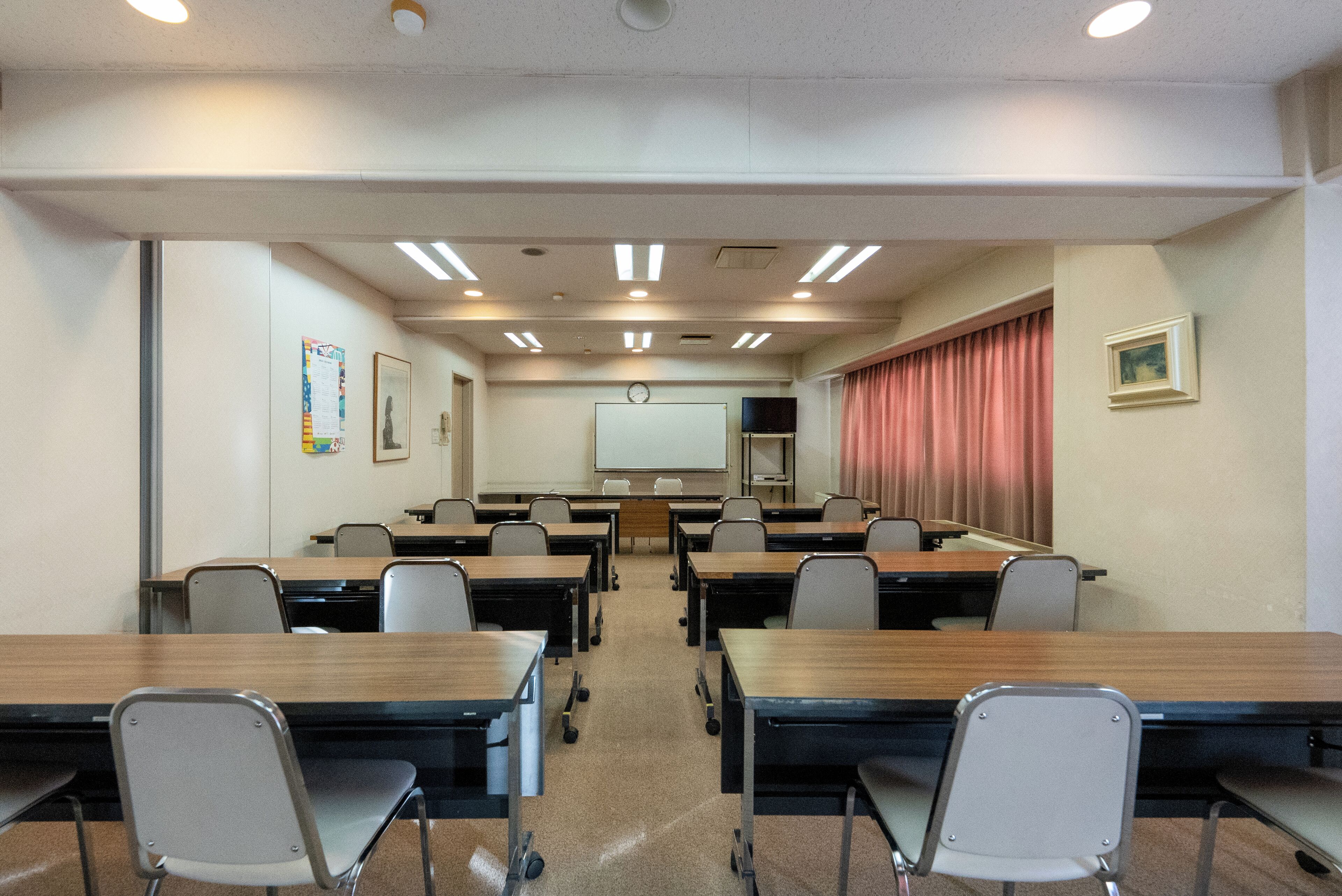 A conference room with tables and chairs, a whiteboard, and a projector screen.