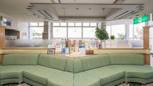 Una zona de recepción con un sofá verde, mostrador de recepción y un amplio ventanal.